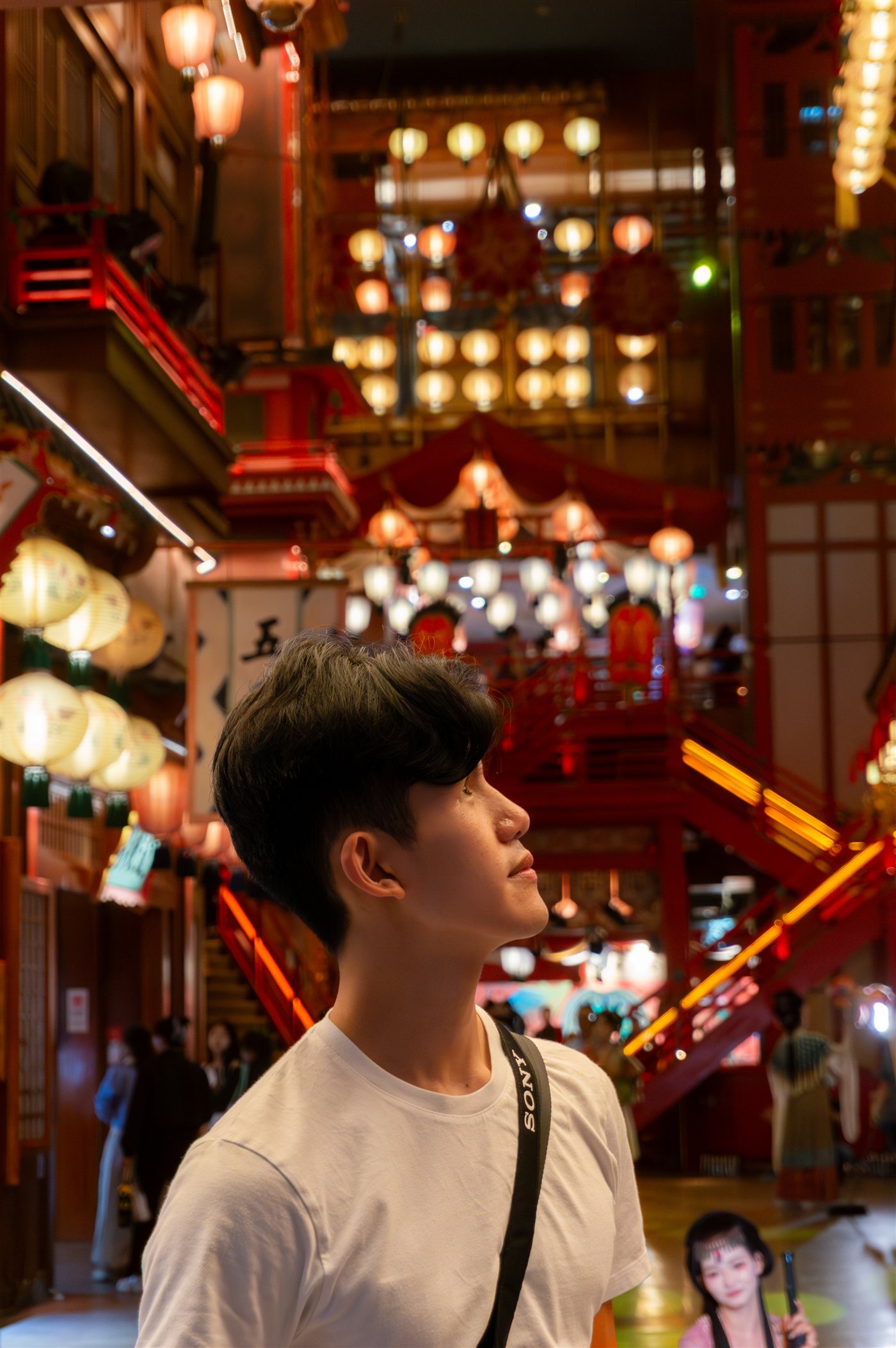 Jack Chung looking up at warm paper lanterns glowing in a dark lantern-lit street at night